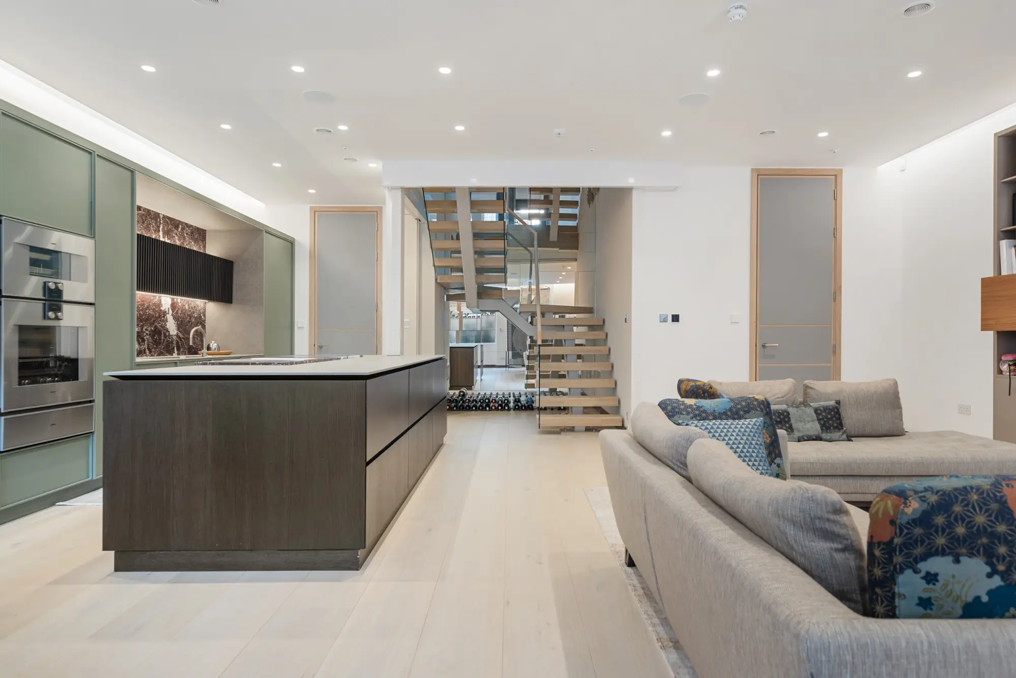 Open-plan kitchen, floating oak staircase and living area in a renovated South Kensington mews house