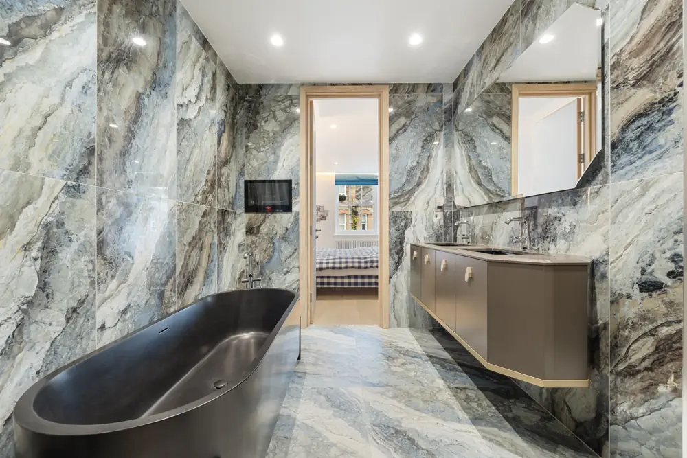 Marble bathroom with a dark freestanding bath